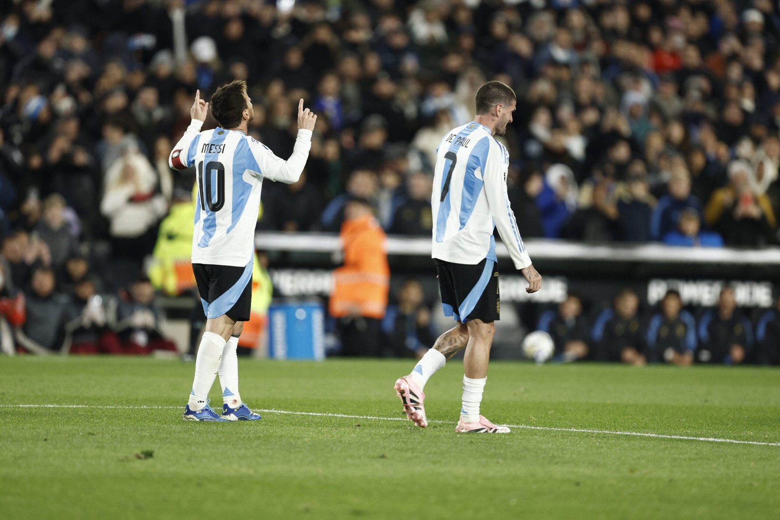Lionel Messi señala al cielo junto a Rodrigo De Paul durante un partido de la Selección Argentina.