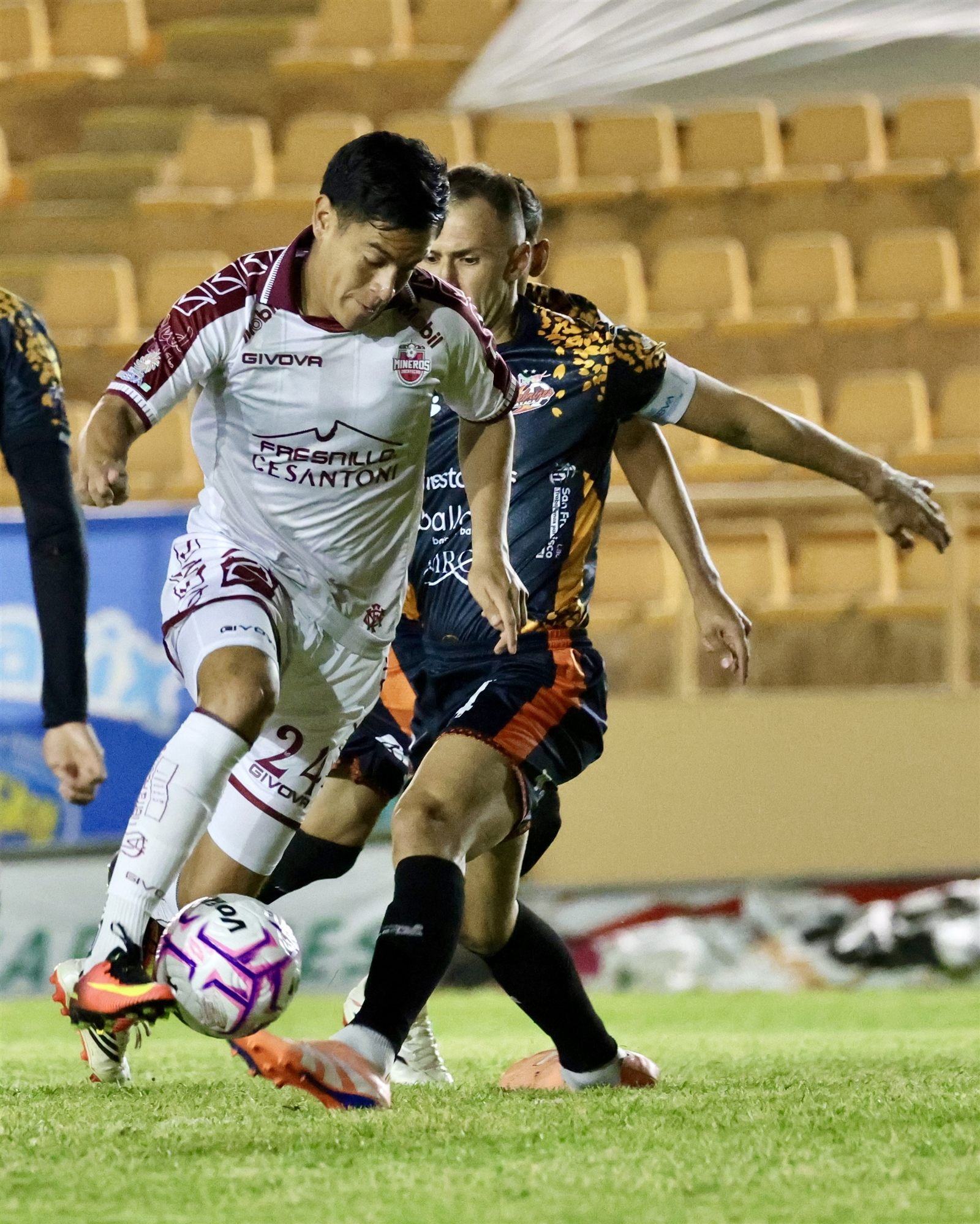 Jugador de Mineros de Zacatecas con el número 24 conduce el balón ante la marca de un jugador de Alebrijes de Oaxaca en el Estadio Tecnológico