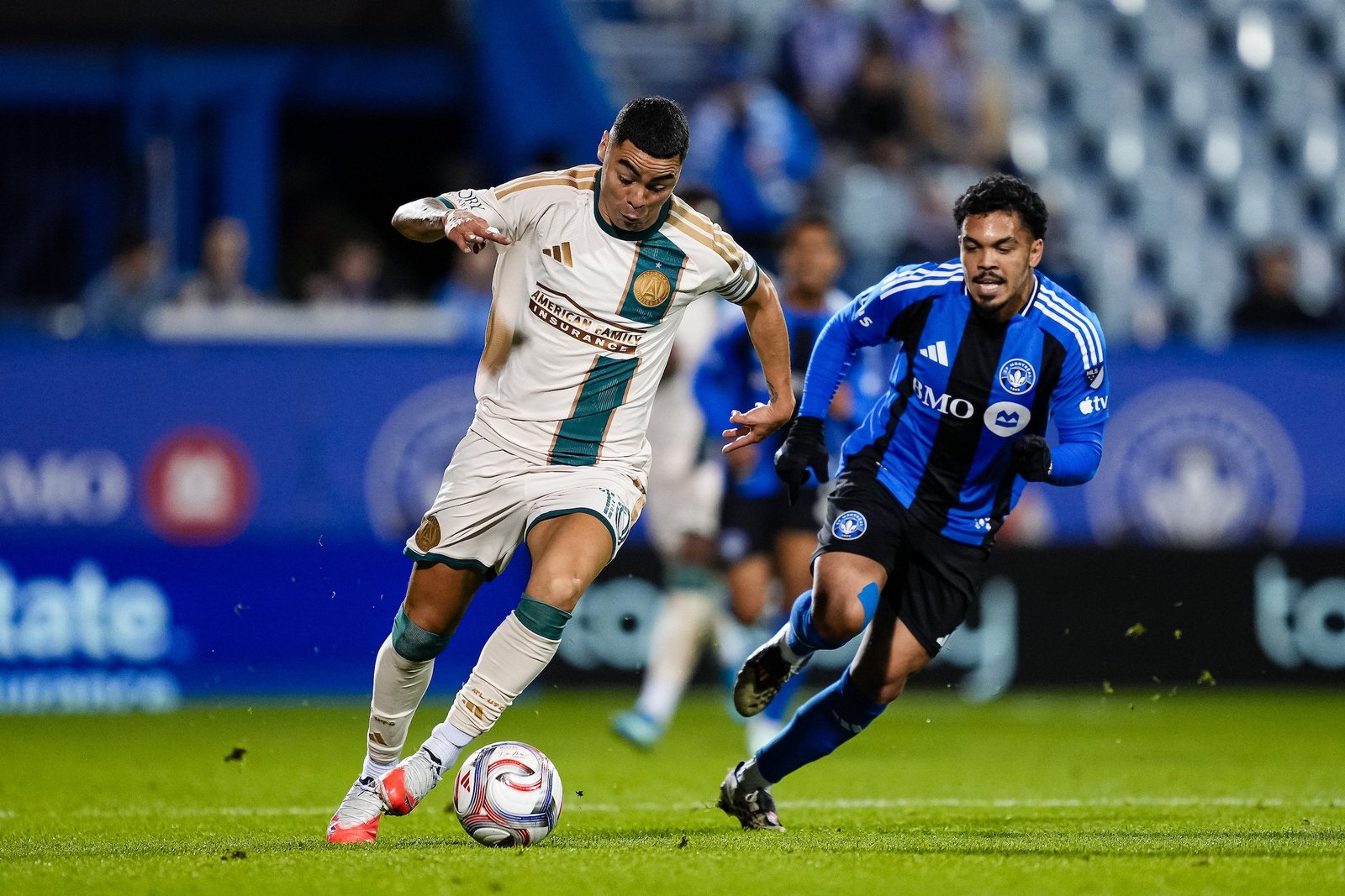 Miguel Almirón, de Atlanta United con el uniforme blanco, conduce el balón ante la marca de un jugador de CF Montréal con la camiseta azul y negra.