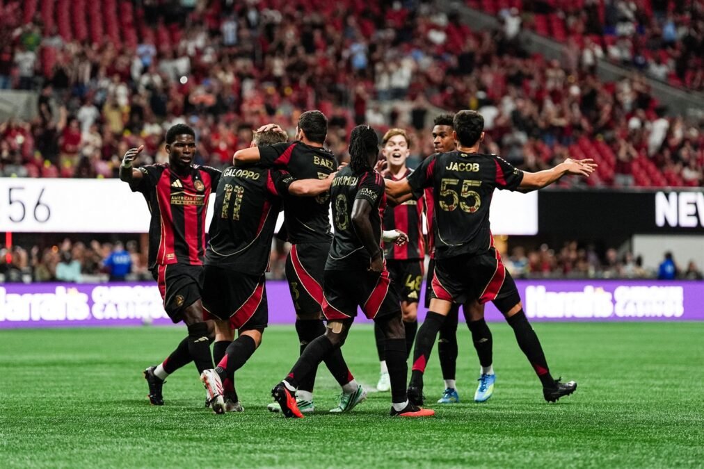 Jugadores del Atlanta United celebran con Giuliano Galoppo tras un gol en el Mercedes-Benz Stadium, con las gradas llenas al fondo.