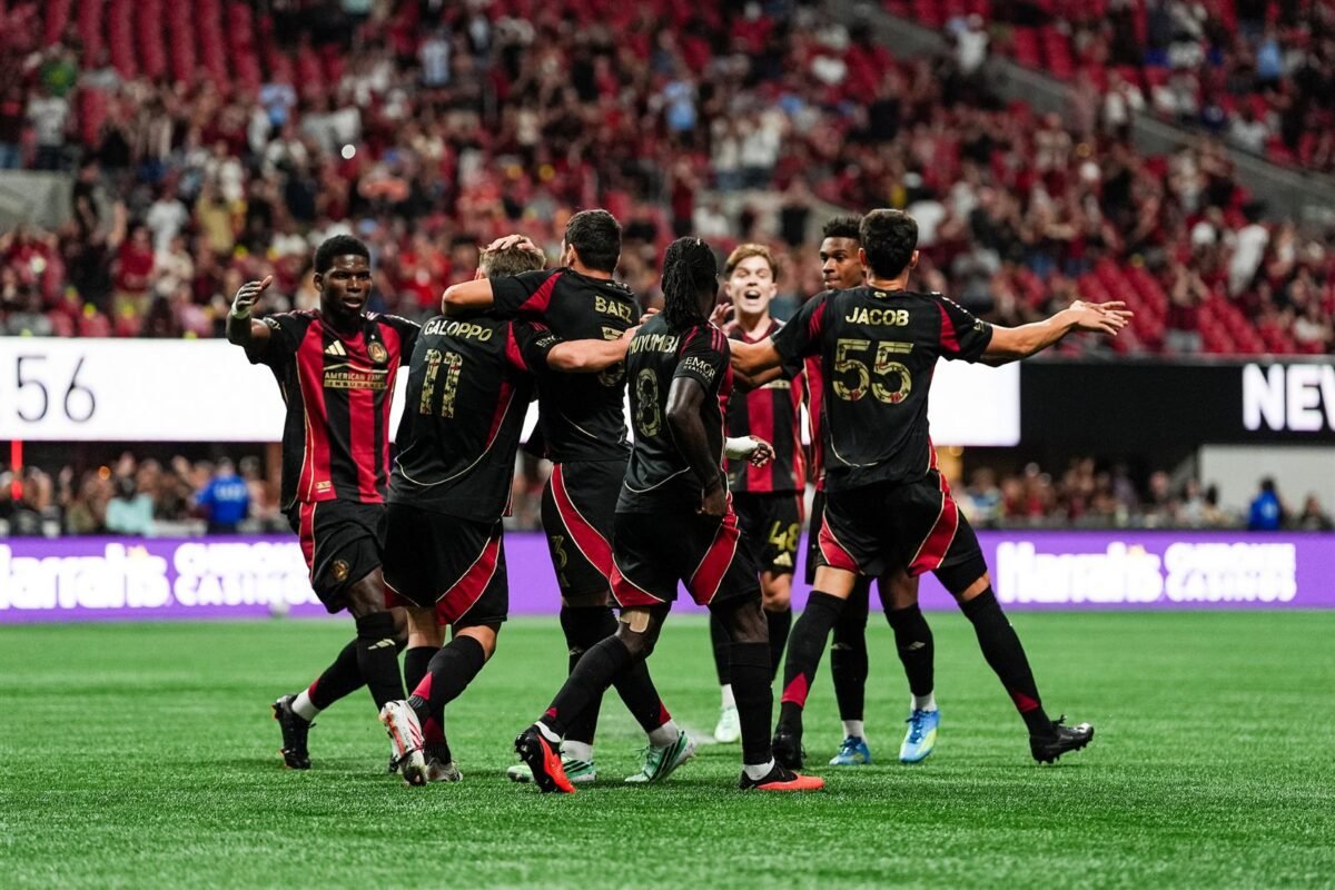 Jugadores del Atlanta United celebran con Giuliano Galoppo tras un gol en el Mercedes-Benz Stadium, con las gradas llenas al fondo.