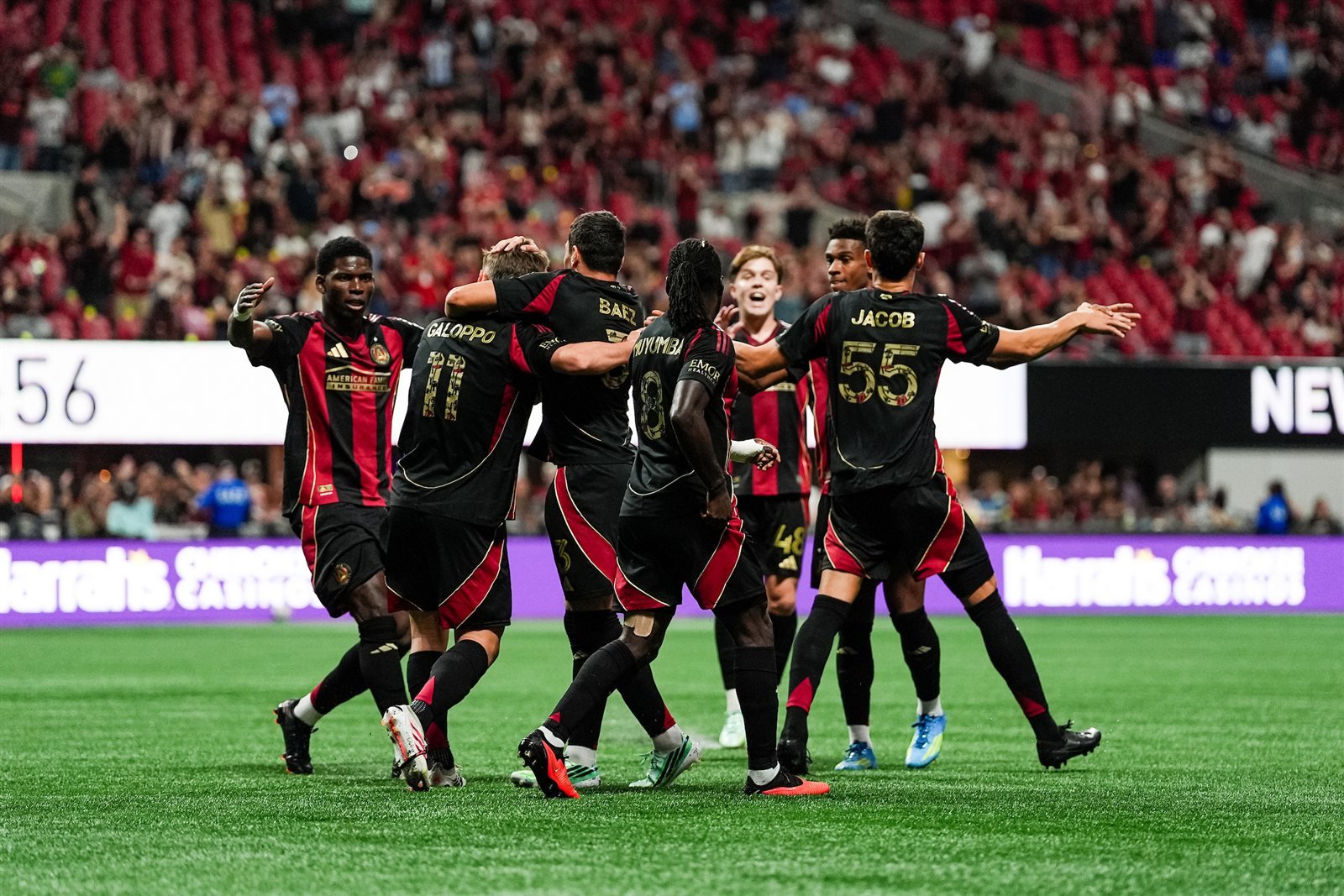 Jugadores del Atlanta United celebran con Giuliano Galoppo tras un gol en el Mercedes-Benz Stadium, con las gradas llenas al fondo.