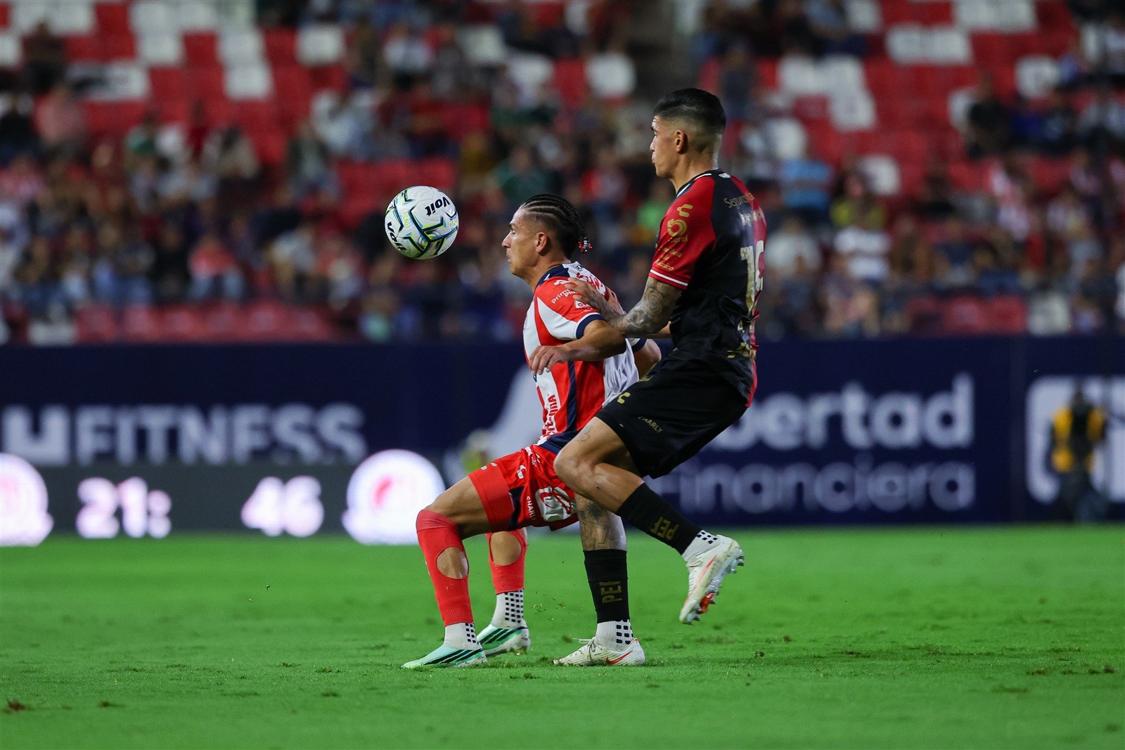 Jugador del Atlético de San Luis protege el balón ante la marca de un jugador de Atlas en el Estadio Libertad Financiera