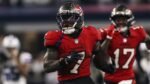 Bucky Irving, corredor de los Buccaneers de Tampa Bay, avanza con el balón durante una carrera en el AT&T Stadium, con un compañero detrás.