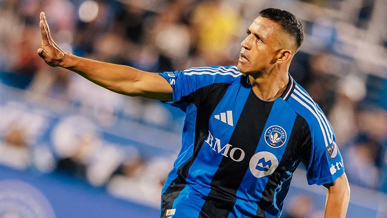 Un jugador de CF Montréal con la camiseta azul y negra levanta la mano durante un partido de la MLS.