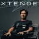 Checo Pérez posa sentado con la playera de Cadillac Formula 1 Team junto a la palabra Extended, que anuncia la extensión de su contrato