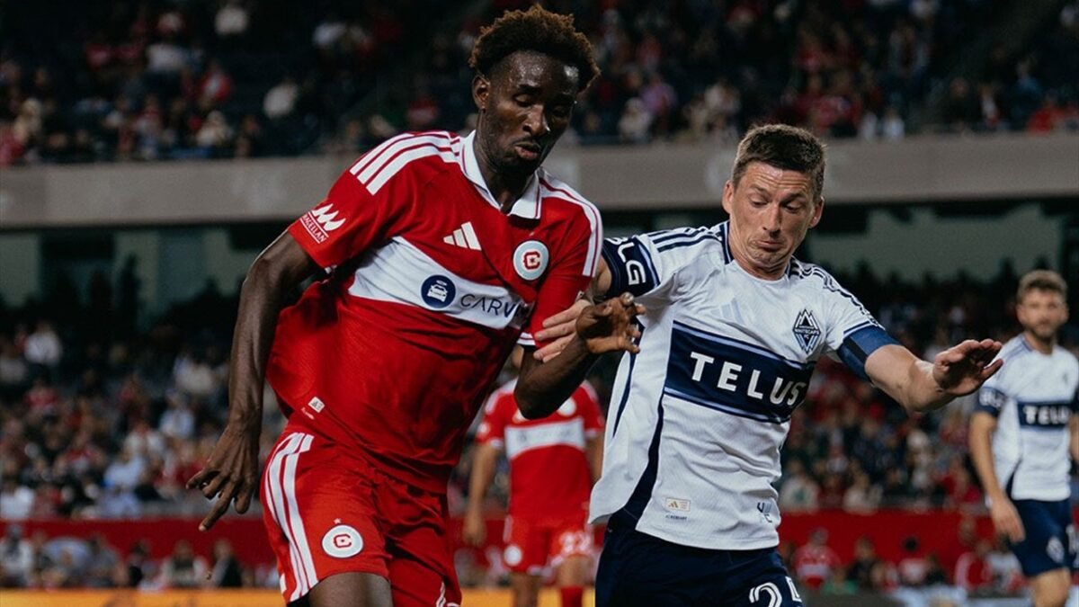 Un jugador del Chicago Fire de camiseta roja disputa el balón con un jugador de Vancouver Whitecaps en un partido de la MLS.