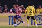 Un joven jugador de Chivas conduce el balón frente a un rival del América con el número 2 durante el Clásico Nacional amistoso en Oakland.