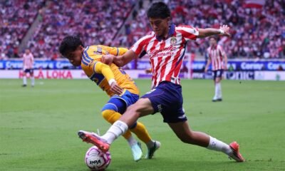 Un jugador de Chivas y uno de Tigres disputan el balón en el Estadio Akron