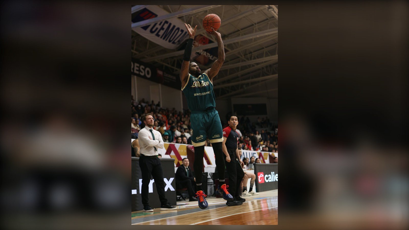 Un jugador de Diablos Rojos con la camiseta verde lanza un triple en el Gimnasio Marcelino González durante la serie del Play-In ante Mineros.