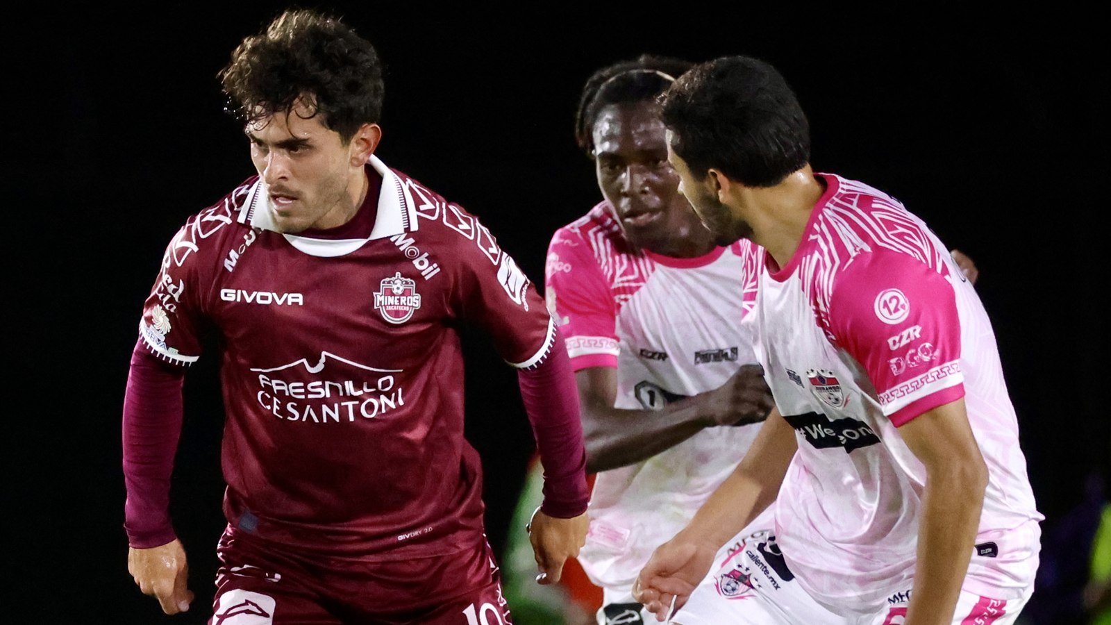 Jugador de Mineros de Zacatecas con el número 19 conduce el balón ante dos rivales de Alacranes de Durango.
