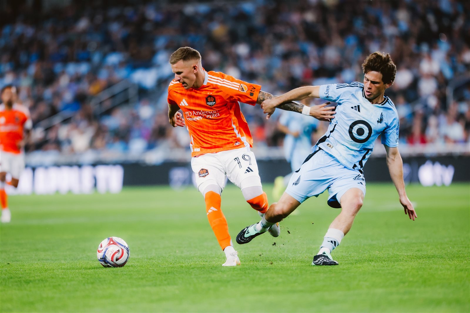 Jugador del Houston Dynamo con el número 19 protege el balón ante un rival de Minnesota United en el Allianz Field.