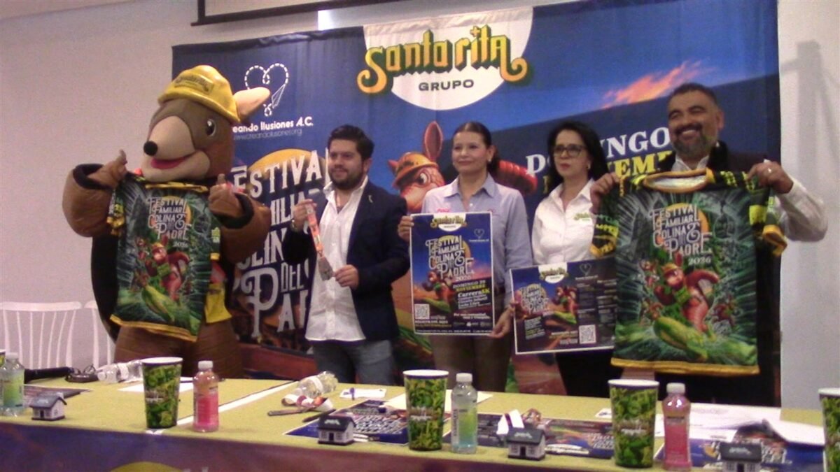 Presentación del Festival Familiar Colinas del Padre 2026 con la botarga del armadillo, playeras del evento y carteles, frente a la manta de Grupo Santa Rita