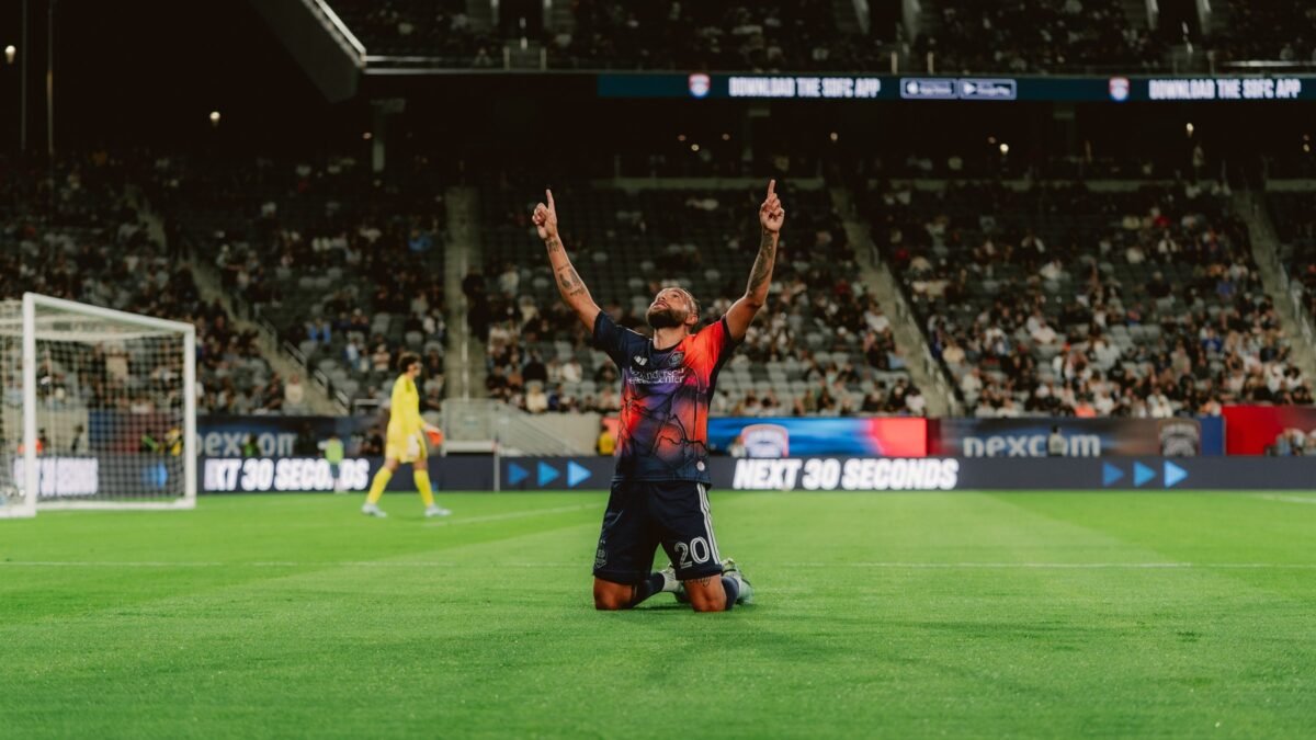 Guilherme, del Houston Dynamo con el número 20, celebra de rodillas con los dos índices hacia el cielo tras un gol en el Snapdragon Stadium, con el portero de San Diego FC al fondo.