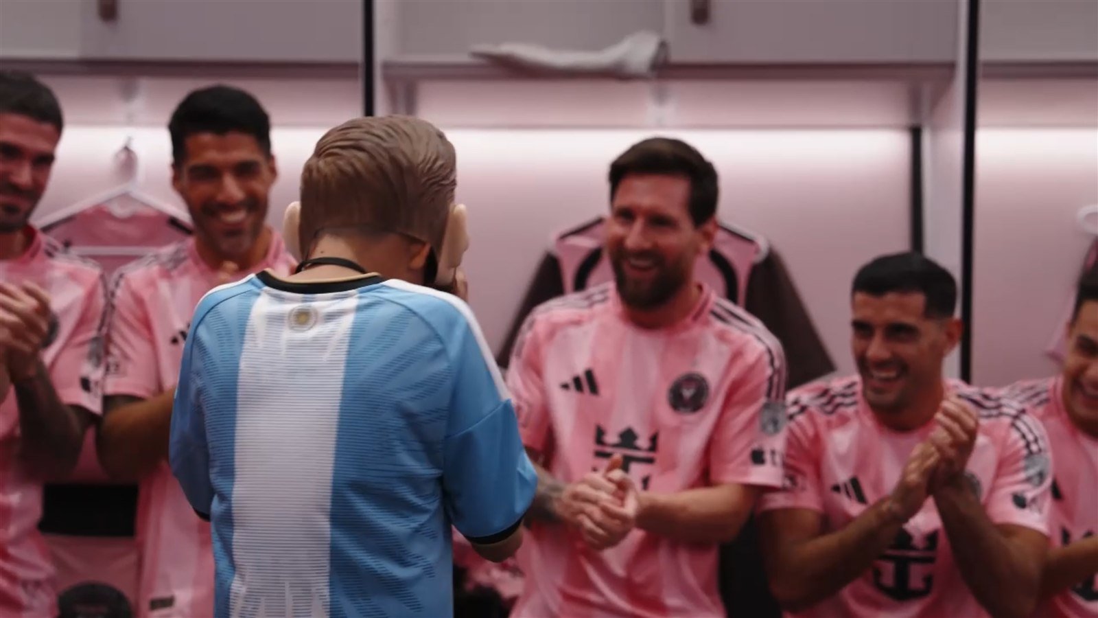 Un niño de la experiencia Make-A-Wish, de espaldas, frente a Lionel Messi, Luis Suárez y otros jugadores del Inter Miami en el vestuario del Nu Stadium