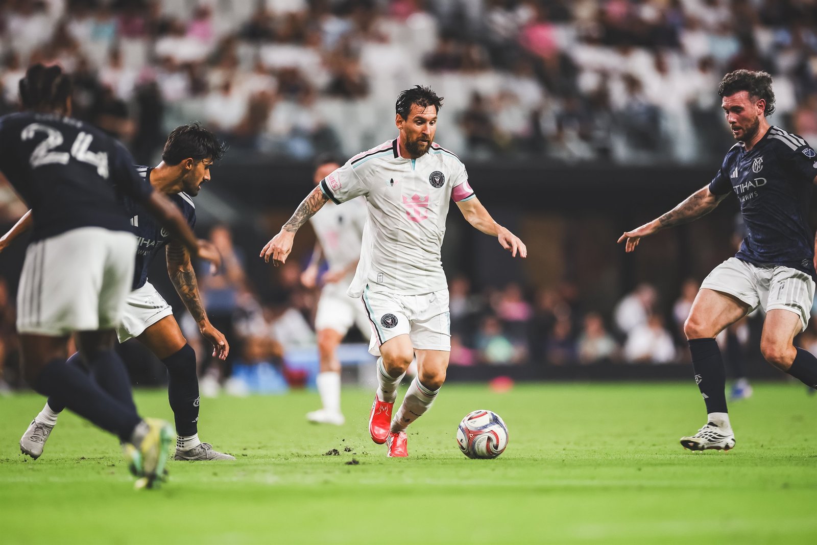 Lionel Messi, capitán del Inter Miami con el brazalete rosa, conduce el balón entre jugadores del New York City FC en el Nu Stadium.