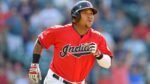 José Ramírez, pelotero de Cleveland, corre hacia primera base tras conectar un batazo, con el estadio desenfocado al fondo.
