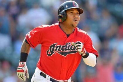 José Ramírez, pelotero de Cleveland, corre hacia primera base tras conectar un batazo, con el estadio desenfocado al fondo.