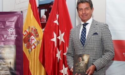 Juan Antonio Hernández, «El Torero Azteca», posa con un ejemplar de «Ponerse Delante» frente a las banderas de España y de la Comunidad de Madrid.