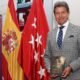 Juan Antonio Hernández, «El Torero Azteca», posa con un ejemplar de «Ponerse Delante» frente a las banderas de España y de la Comunidad de Madrid.