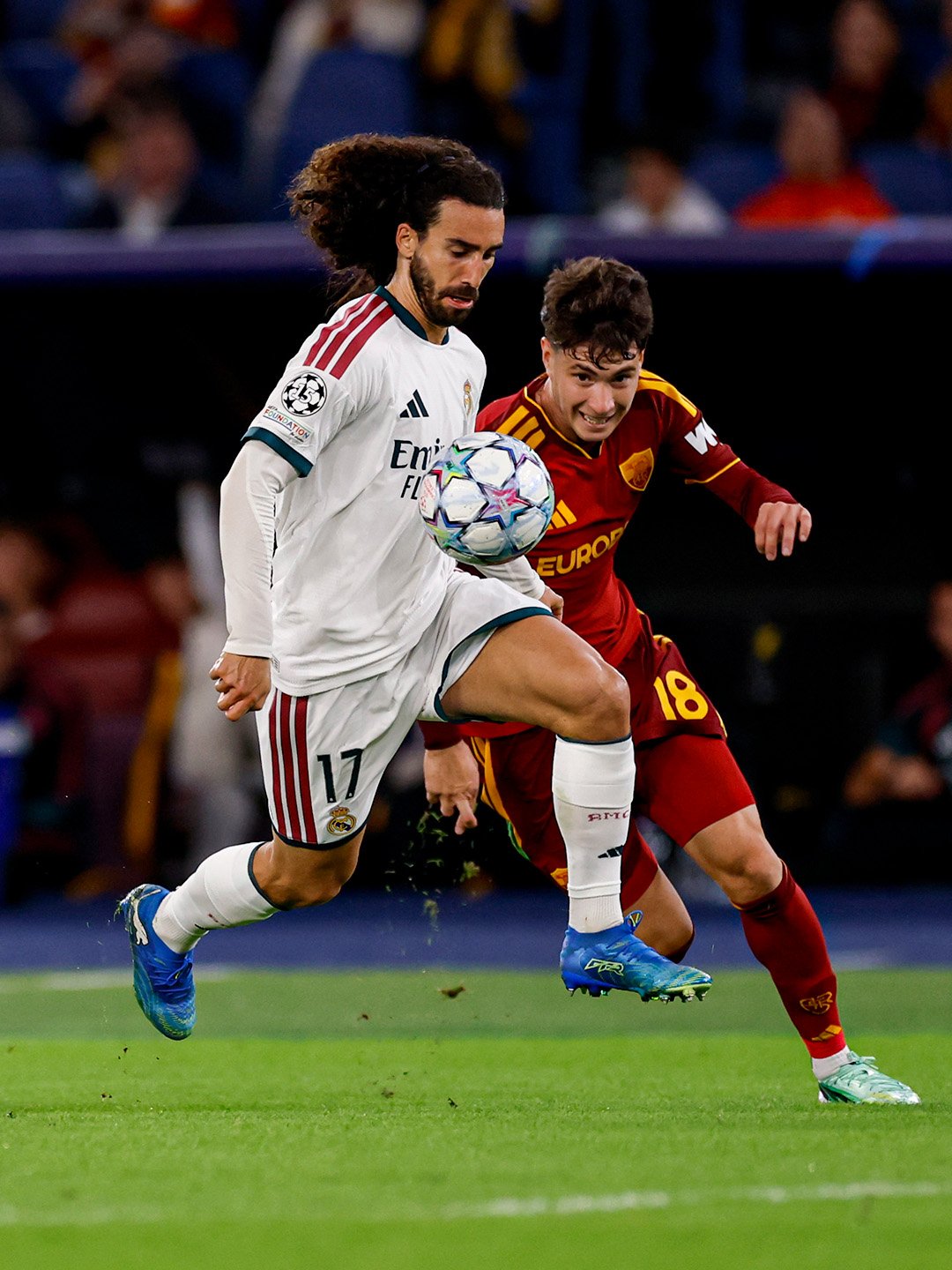 Un jugador del Real Madrid con el número 17 controla el balón ante la presión de un rival de la Roma durante el partido de Champions League.
