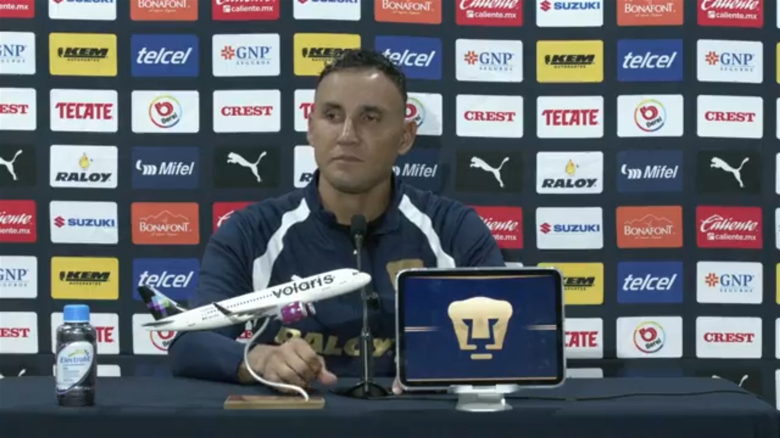 Keylor Navas, capitán de Pumas, en la conferencia de prensa previa al partido ante Cruz Azul, con una maqueta de avión y la tableta del club sobre la mesa.