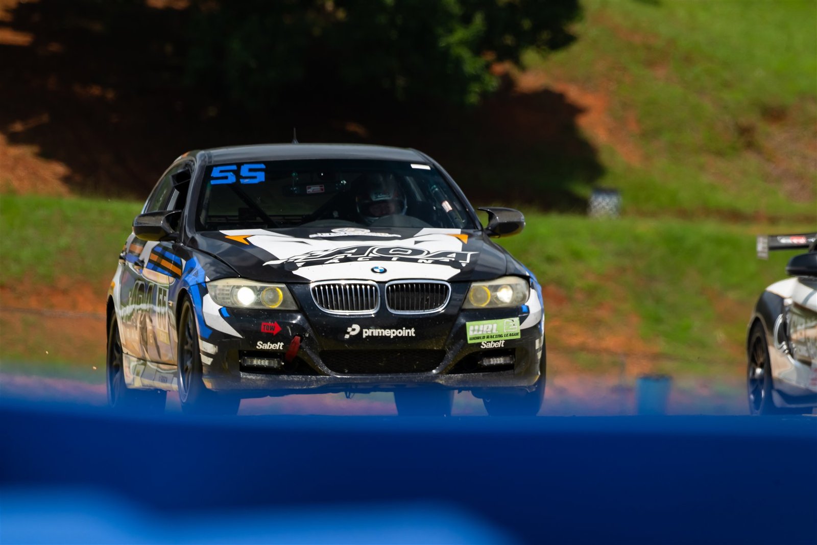El BMW número 55 de AOA Racing, con los logotipos del World Racing League, avanza de frente en la pista.