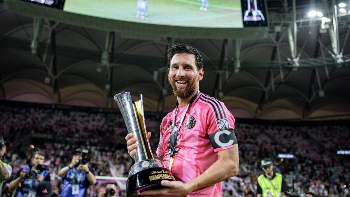 Lionel Messi sonríe con el trofeo de la Campeones Cup en las manos, con la playera rosa de Inter Miami y el brazalete de capitán.