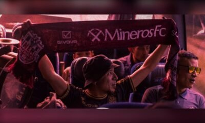 Aficionado de Mineros de Zacatecas sostiene en alto una bufanda de Mineros FC dentro de un autobús de la Caravana Minera.