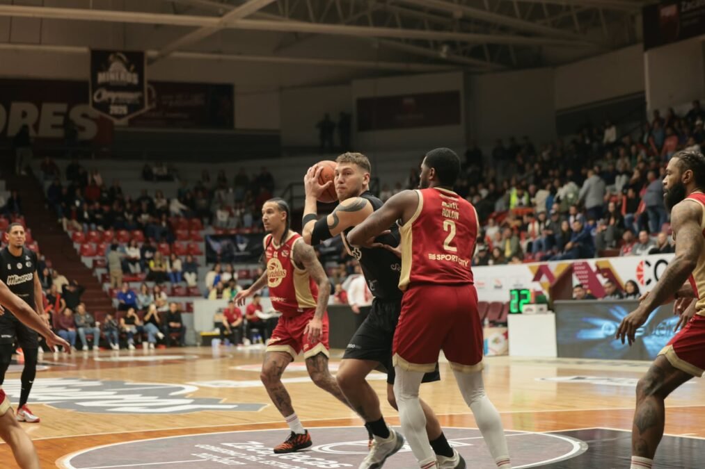 Un jugador de Mineros protege el balón ante la marca de un jugador de Diablos Rojos con el número 2 en el Juego 1 del Play-In.