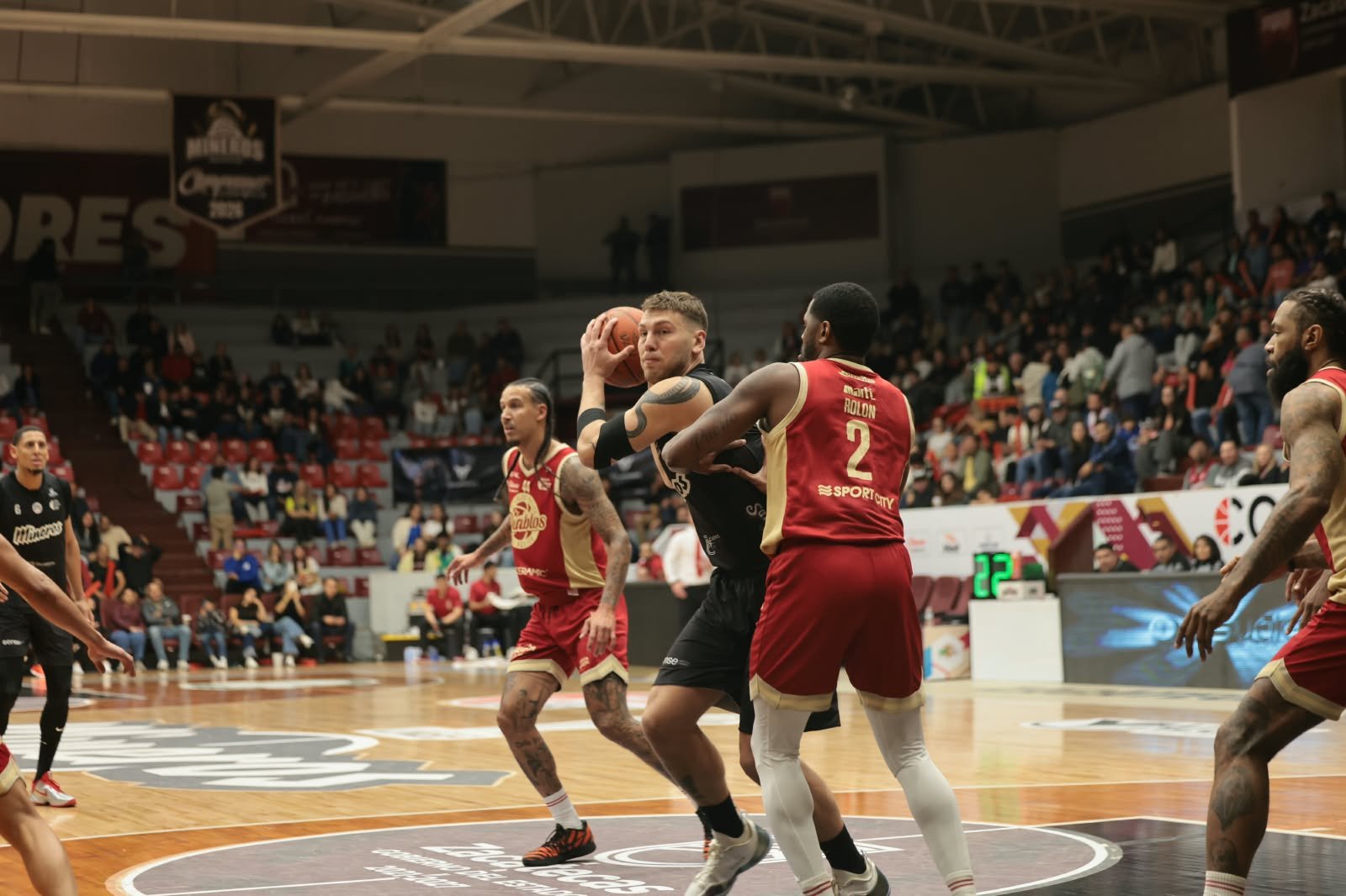 Un jugador de Mineros protege el balón ante la marca de un jugador de Diablos Rojos con el número 2 en el Juego 1 del Play-In.