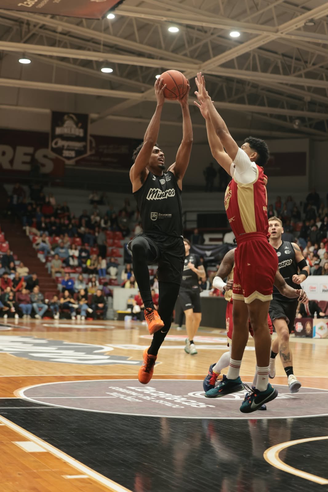 Un jugador de Mineros con el número 3 sube al aro con el balón ante la marca de un jugador de Diablos Rojos en el Juego 1 del Play-In.