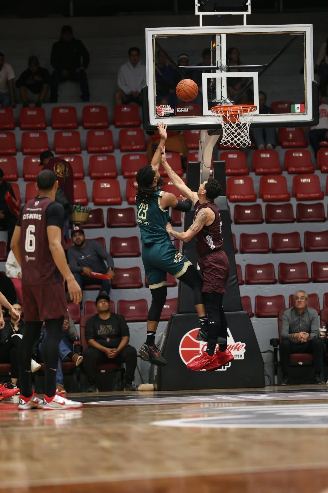 Un jugador de Diablos Rojos con el número 23 lanza al aro ante la marca de un jugador de Mineros en el Juego 2 del Play-In.