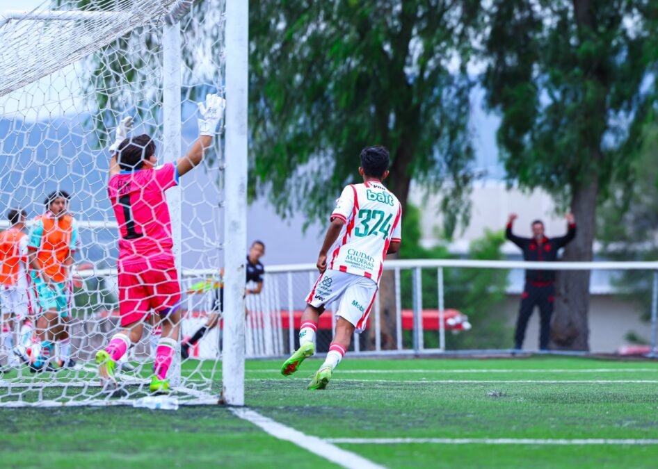 Un jugador de Necaxa con el número 324 corre junto a la portería mientras el portero rival levanta los brazos en un partido de la TDP