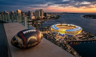 Ilustración conceptual sobre si los dueños de los Padres pueden comprar a los Chargers: un balón con rayos de los Chargers y costuras de béisbol frente a un estadio imaginario en San Diego.