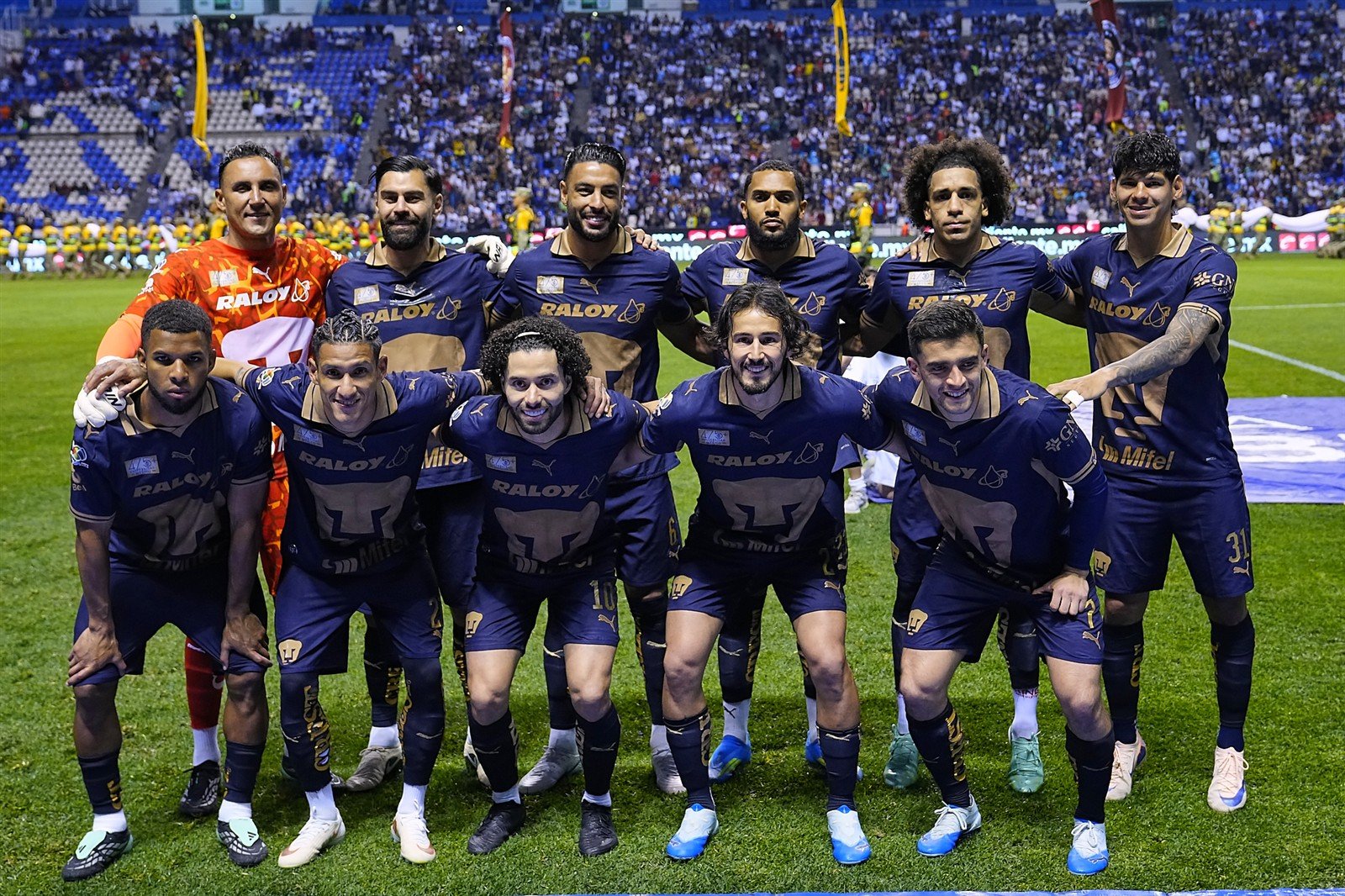 Once inicial de Pumas, con Keylor Navas con jersey naranja, posa en el Estadio Cuauhtémoc antes del partido ante Puebla