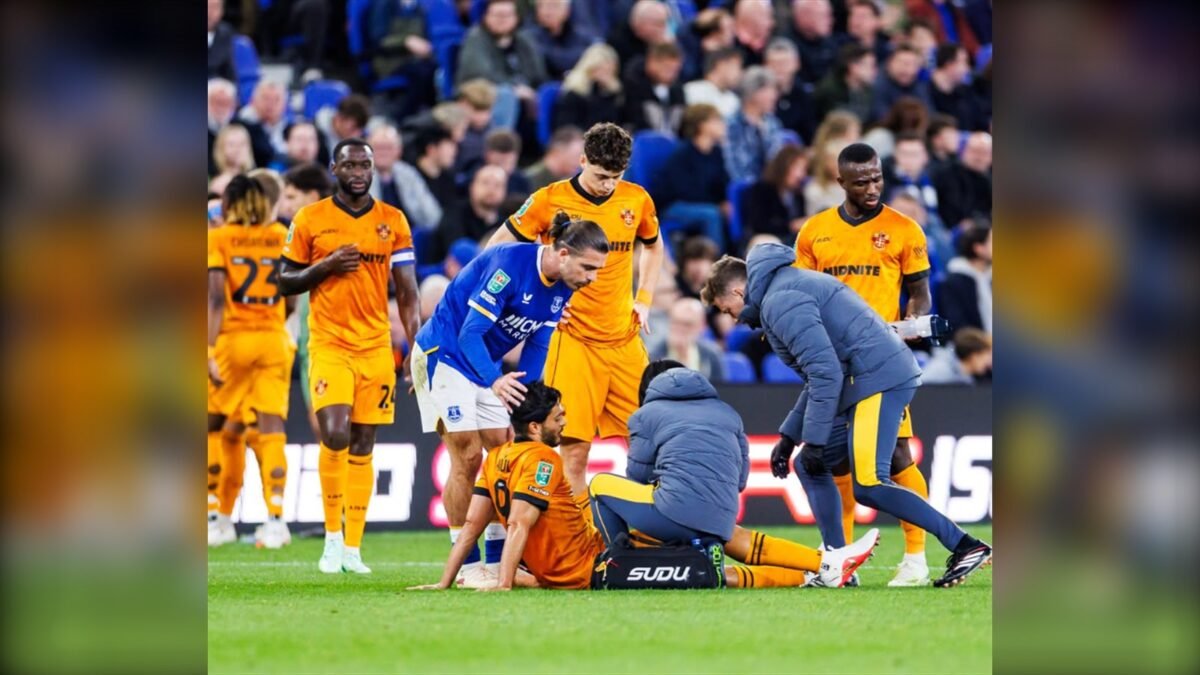 Raúl Jiménez recibe atención médica sentado en el césped durante el partido ante el Everton, con compañeros de los Wolves y el cuerpo médico a su alrededor.