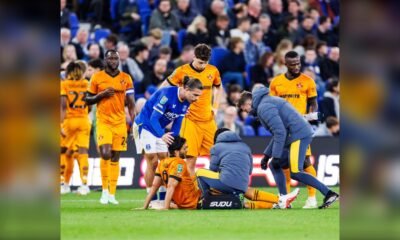 Raúl Jiménez recibe atención médica sentado en el césped durante el partido ante el Everton, con compañeros de los Wolves y el cuerpo médico a su alrededor.