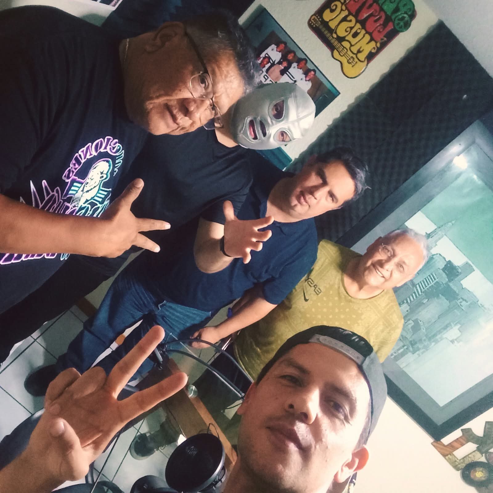 El Santo Jr., con su máscara plateada, junto a cuatro personas en una cabina de radio.