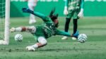 Un portero de Santos Laguna se estira para atajar el balón durante un entrenamiento, con otro portero de pie al fondo.