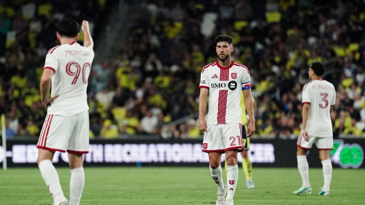 Mediocampista de Toronto FC con el número 21 y el brazalete de capitán, en un partido de la MLS, con dos compañeros al fondo.